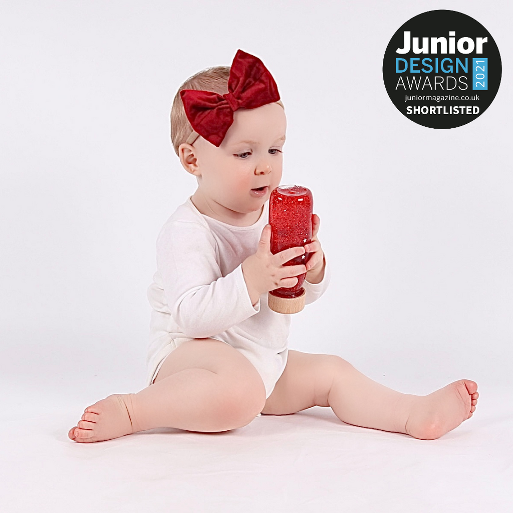 A baby playing with the red petit boum float bottle from their 3-6 month subscription box.