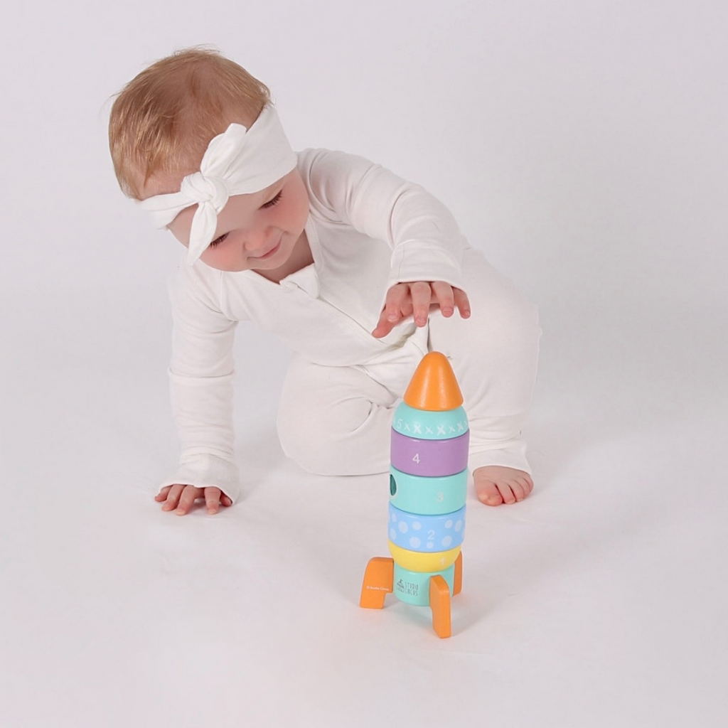 A baby playing with the Studio Circus Peekaboo Panda Stacking Wooden Rocket Tower.