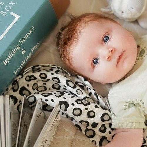 A baby with the black and white printed muslin from the Baby's First Year Subscription Box.