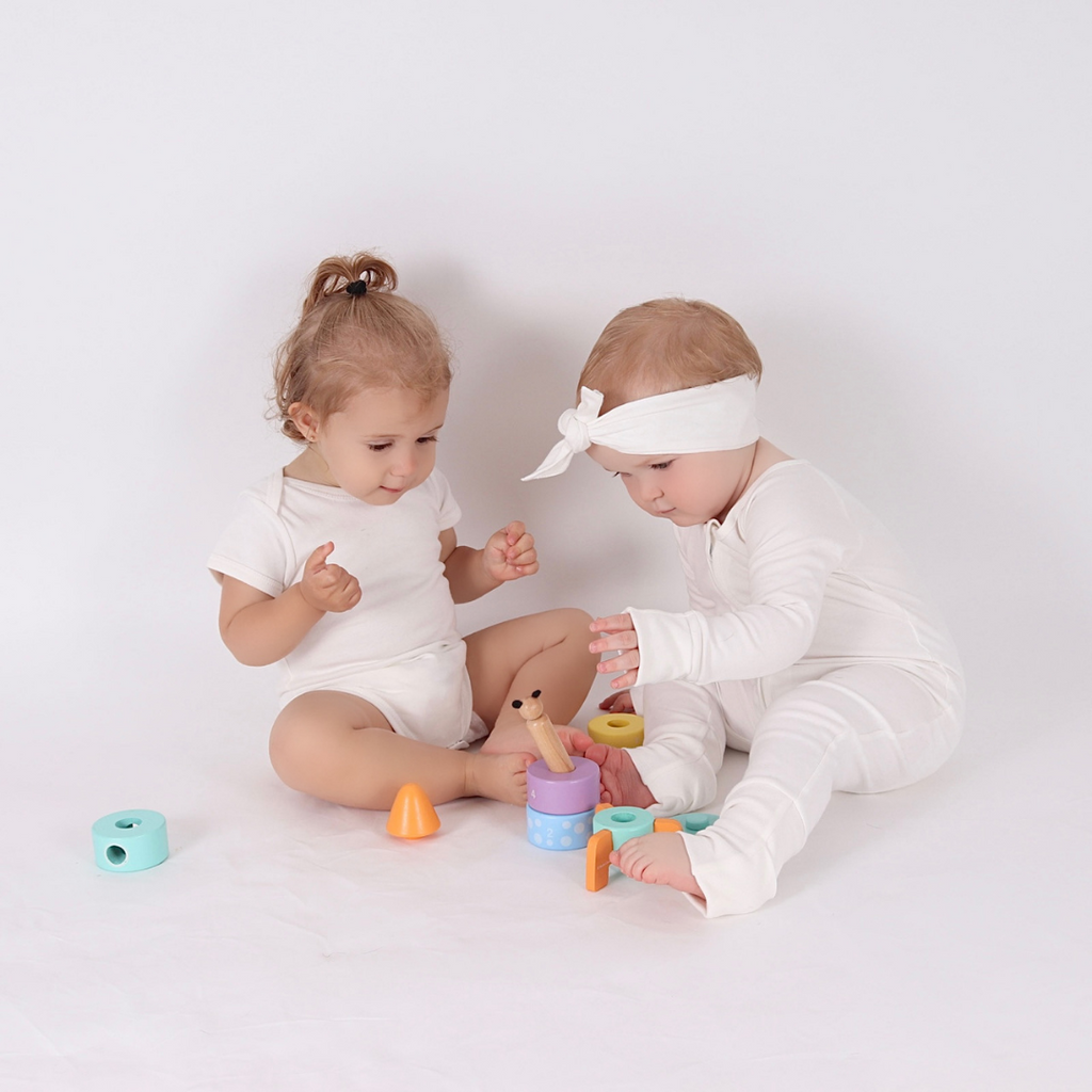 Two baby playing and sharing the Studio Circus Peekaboo Panda Stacking Wooden Rocket Tower.