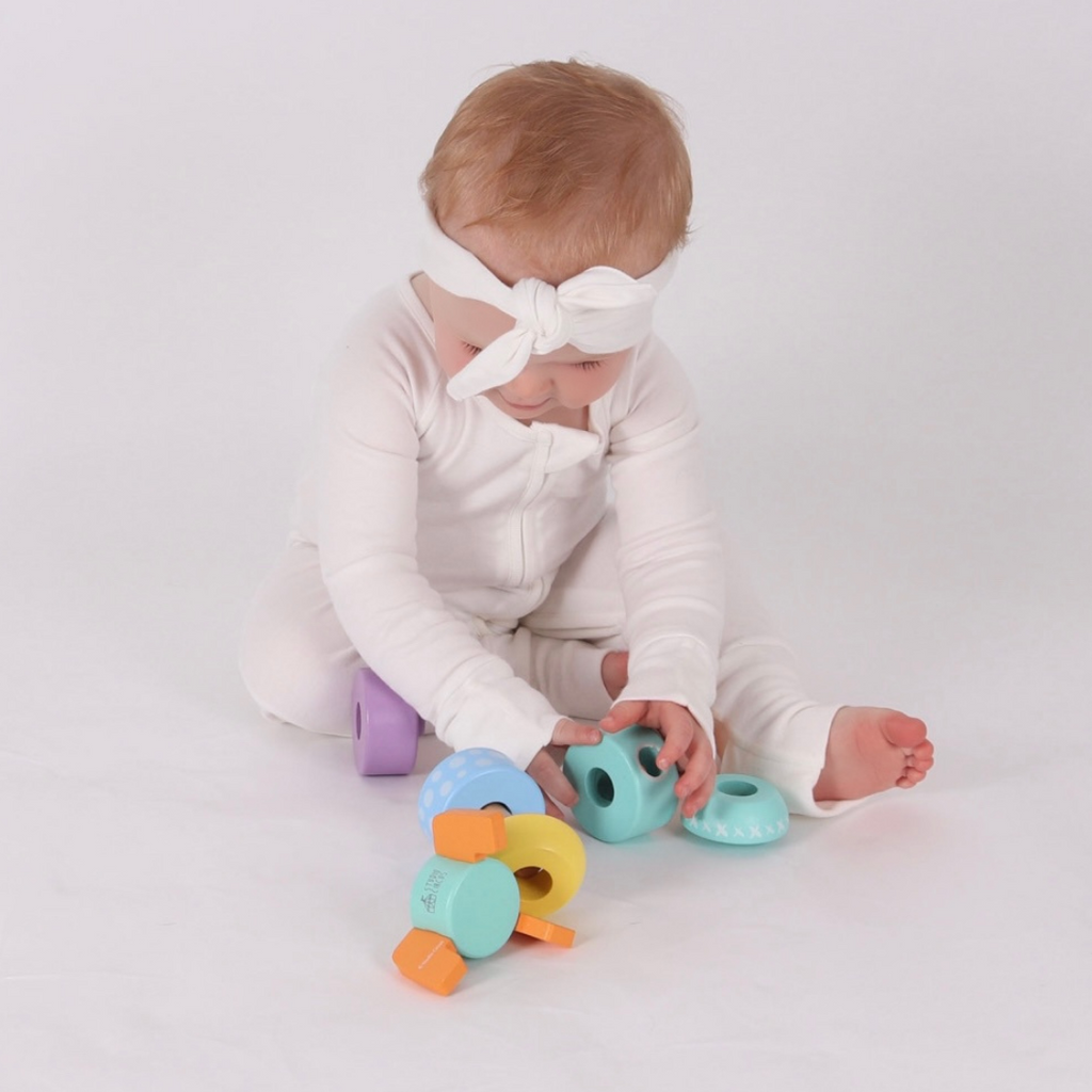 A baby playing with the Studio Circus Peekaboo Panda Stacking Wooden Rocket Tower exploring the wooden pieces.