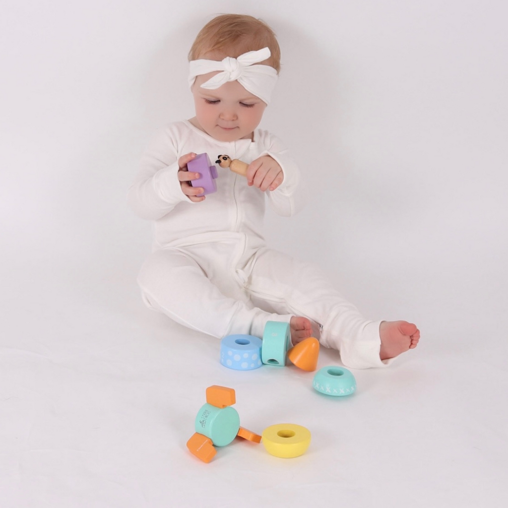 A baby playing and exploring the Wooden Panda from the Studio Circus Peekaboo Panda Stacking Wooden Rocket Tower.