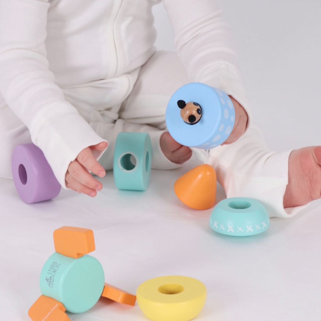 A baby playing with the pieces from the Studio Circus Peekaboo Panda Stacking Wooden Rocket Tower.