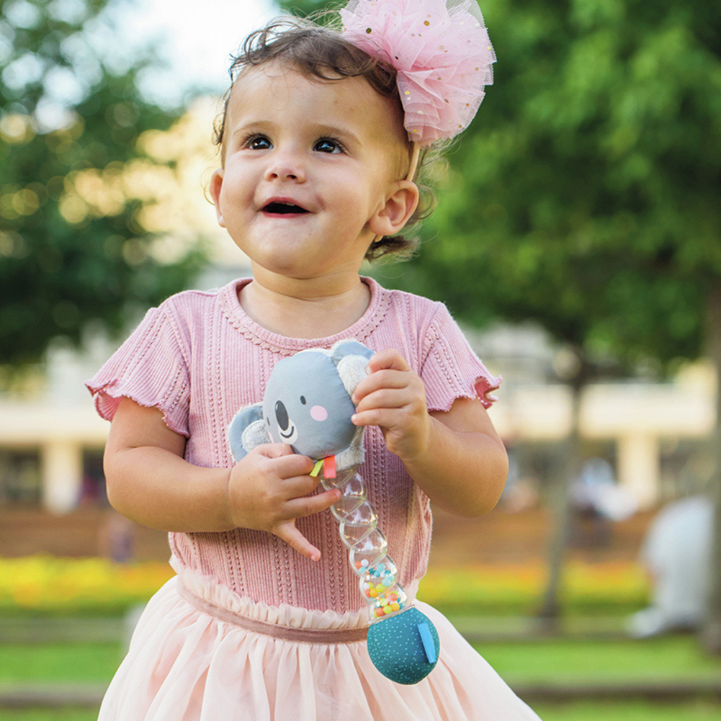 A small child holding the taf toys koala rainstick baby rattle